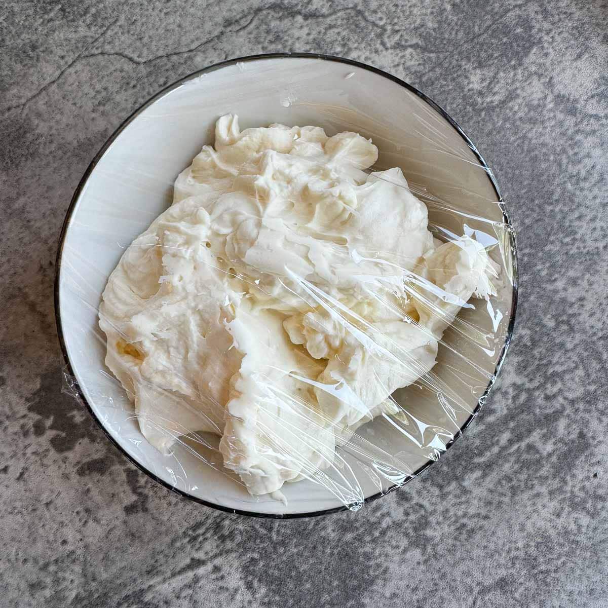 cream cheese batter in a bowl covered in plastic.