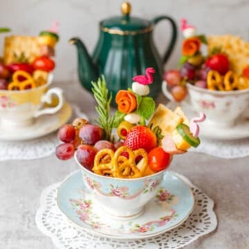 three individual charcuterie cups in teacups with teapot in background.