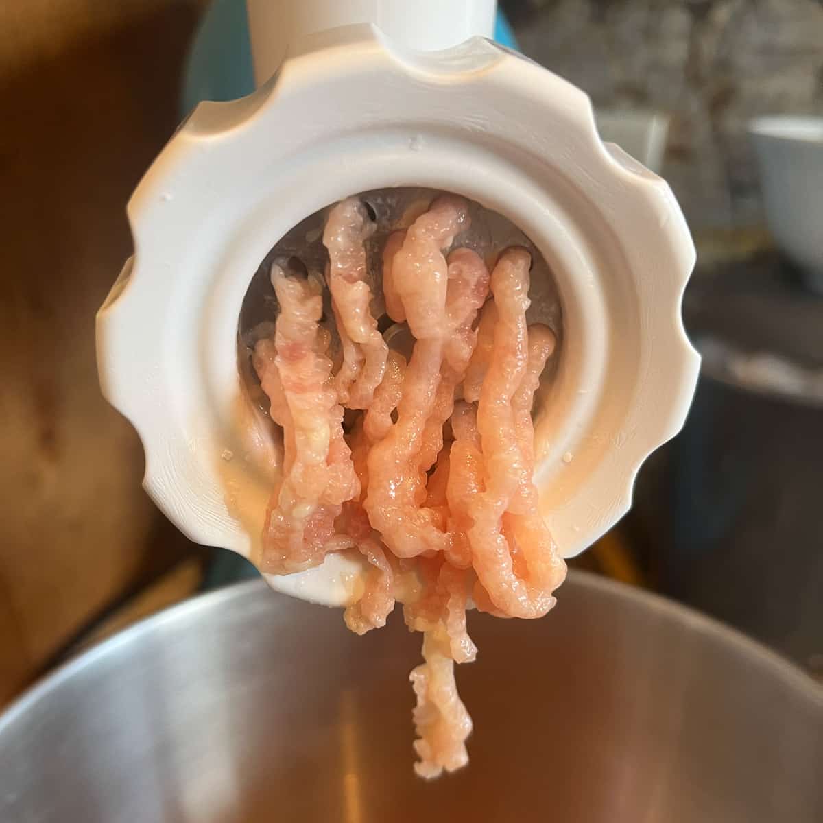 chicken being ground with meat grinder.