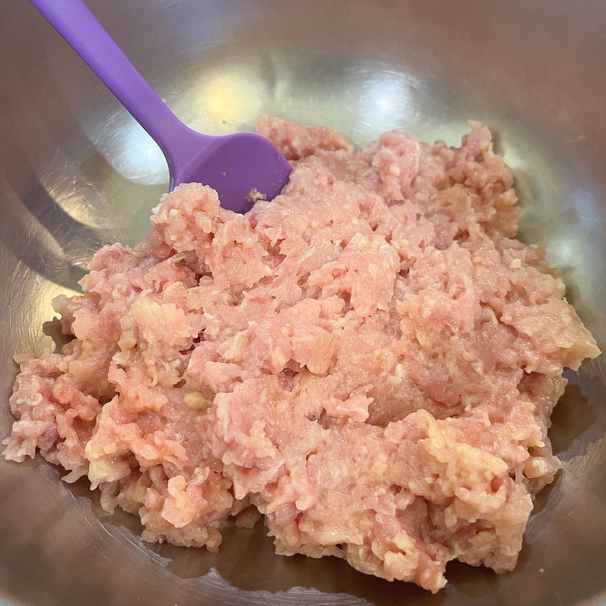 ground turkey in a bowl with a purple spatula.