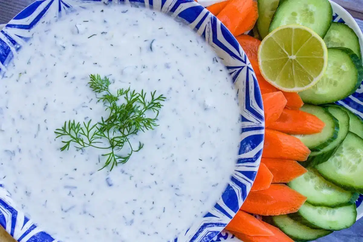 yogurt sauce in a blue and white bowl with sliced veggies.