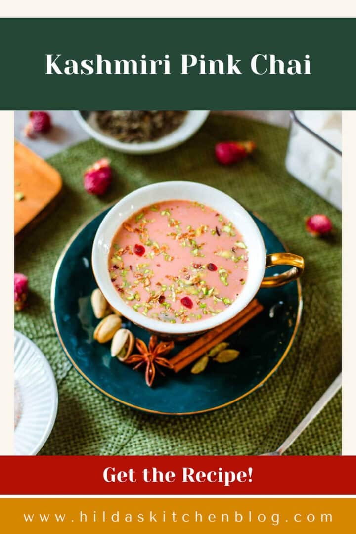 kashmiri chai in teacup surrounded by flowers, tea leaves, sugar cubes, spices.