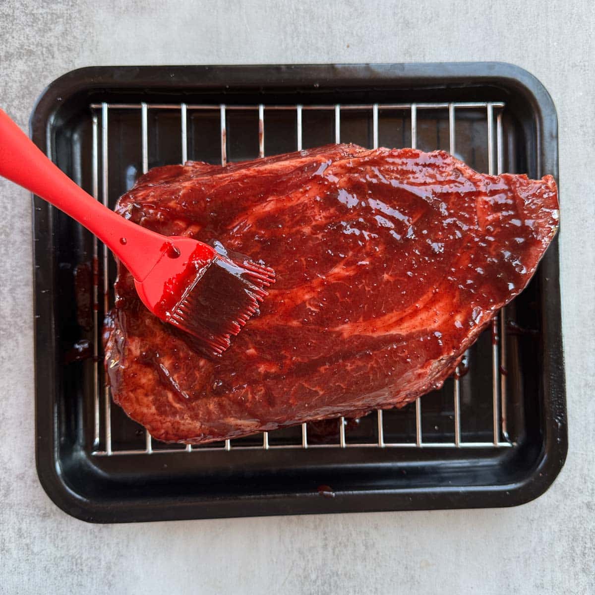 brushing bbq sauce on chuck roast. 