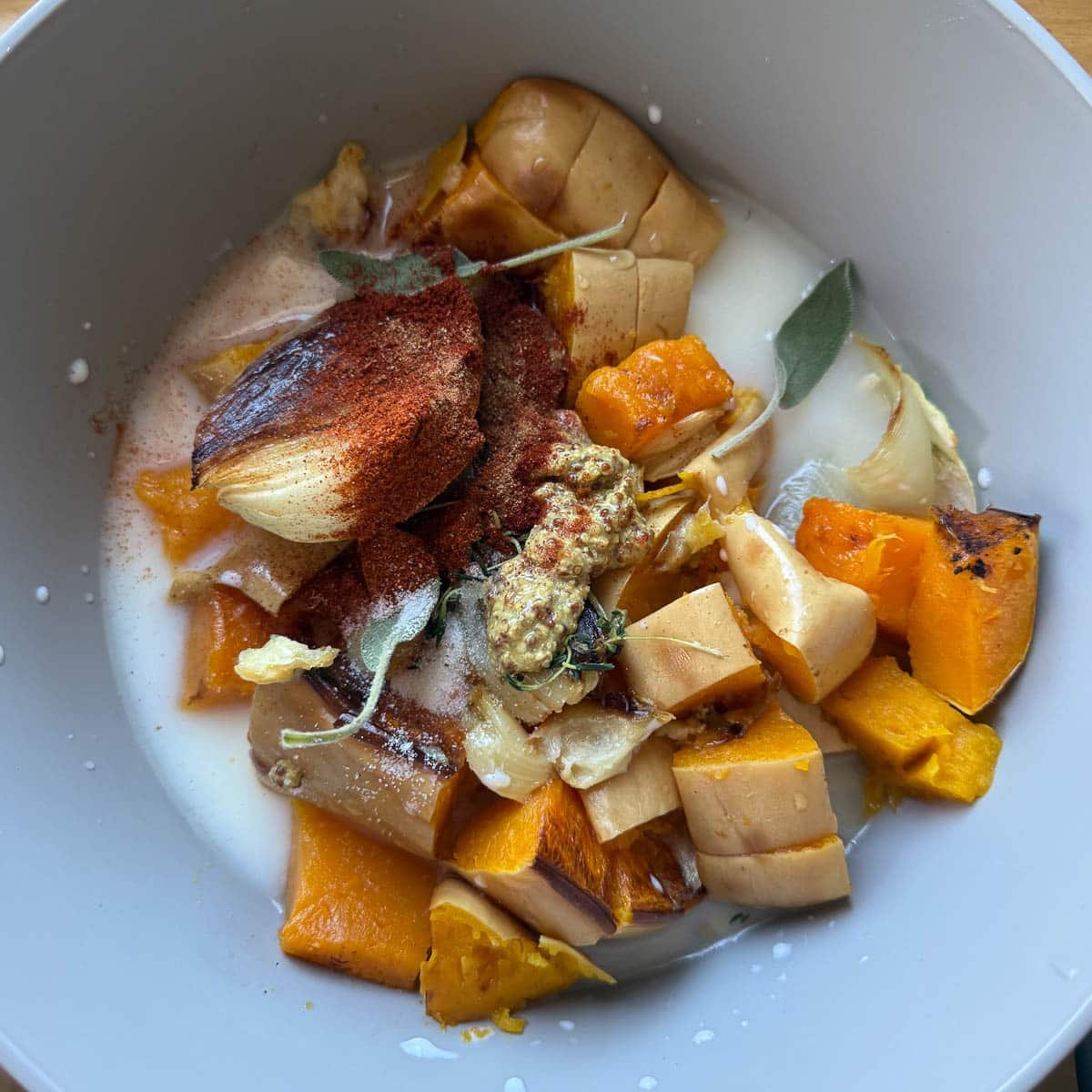 roasted veggies, seasonings, herbs, liquids in bowl before blending.