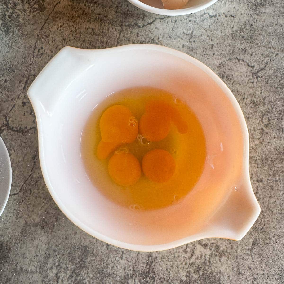 4 cracked eggs in a dish.