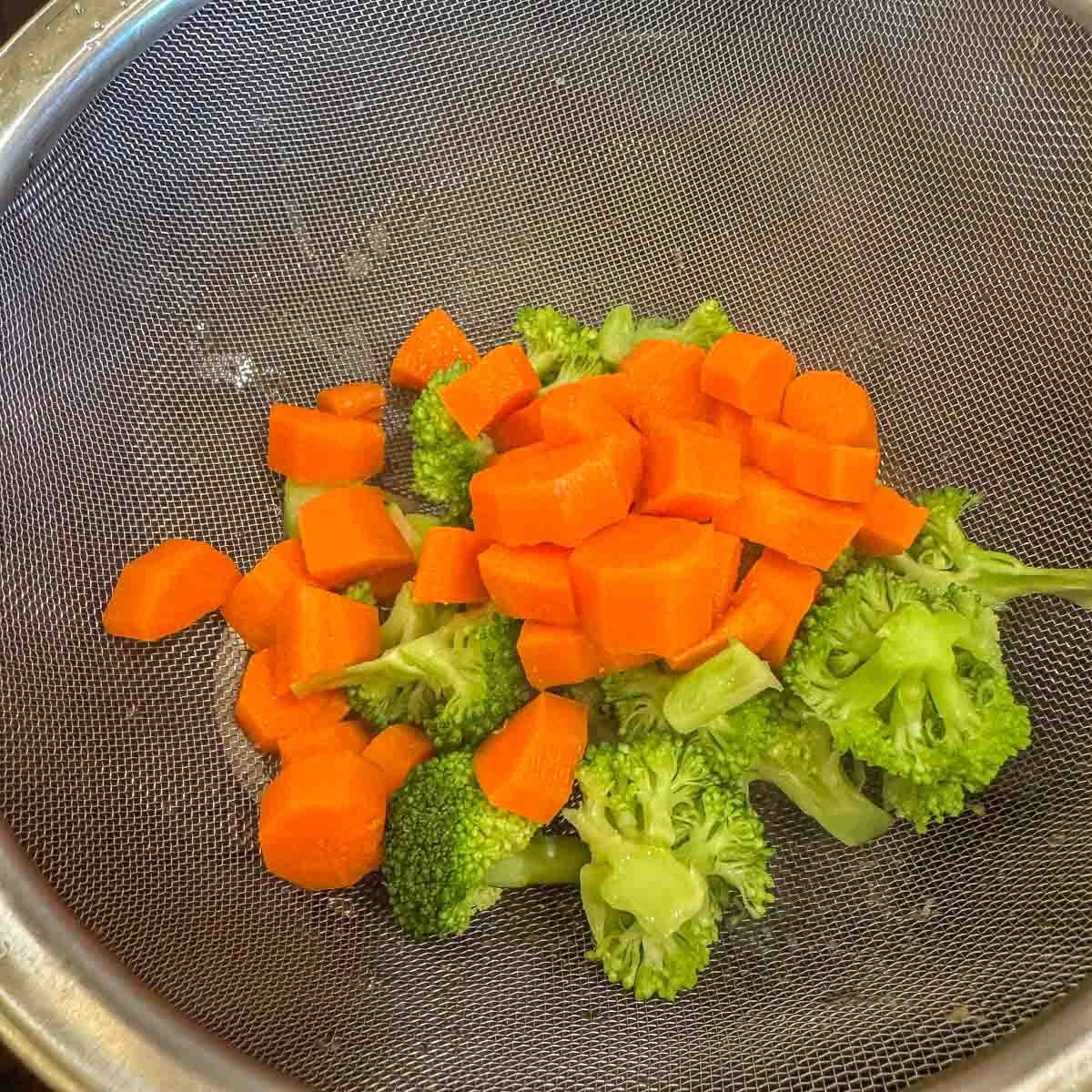 chopped broccoli and carrots in a strainer. 