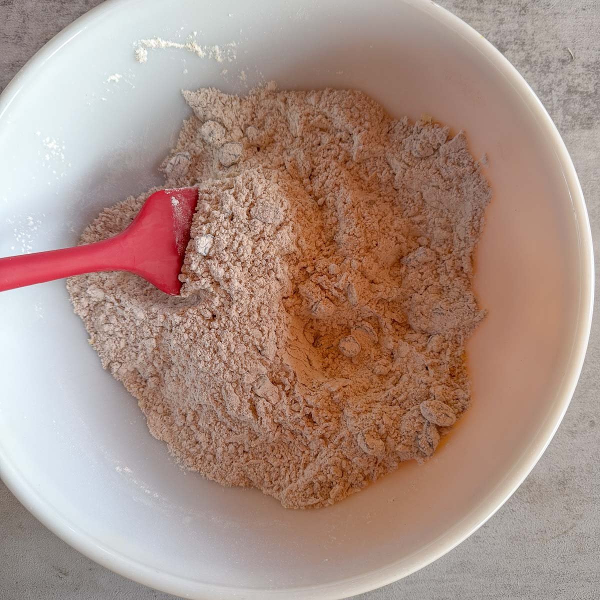 white bowl with flour mixture and red spatula. 
