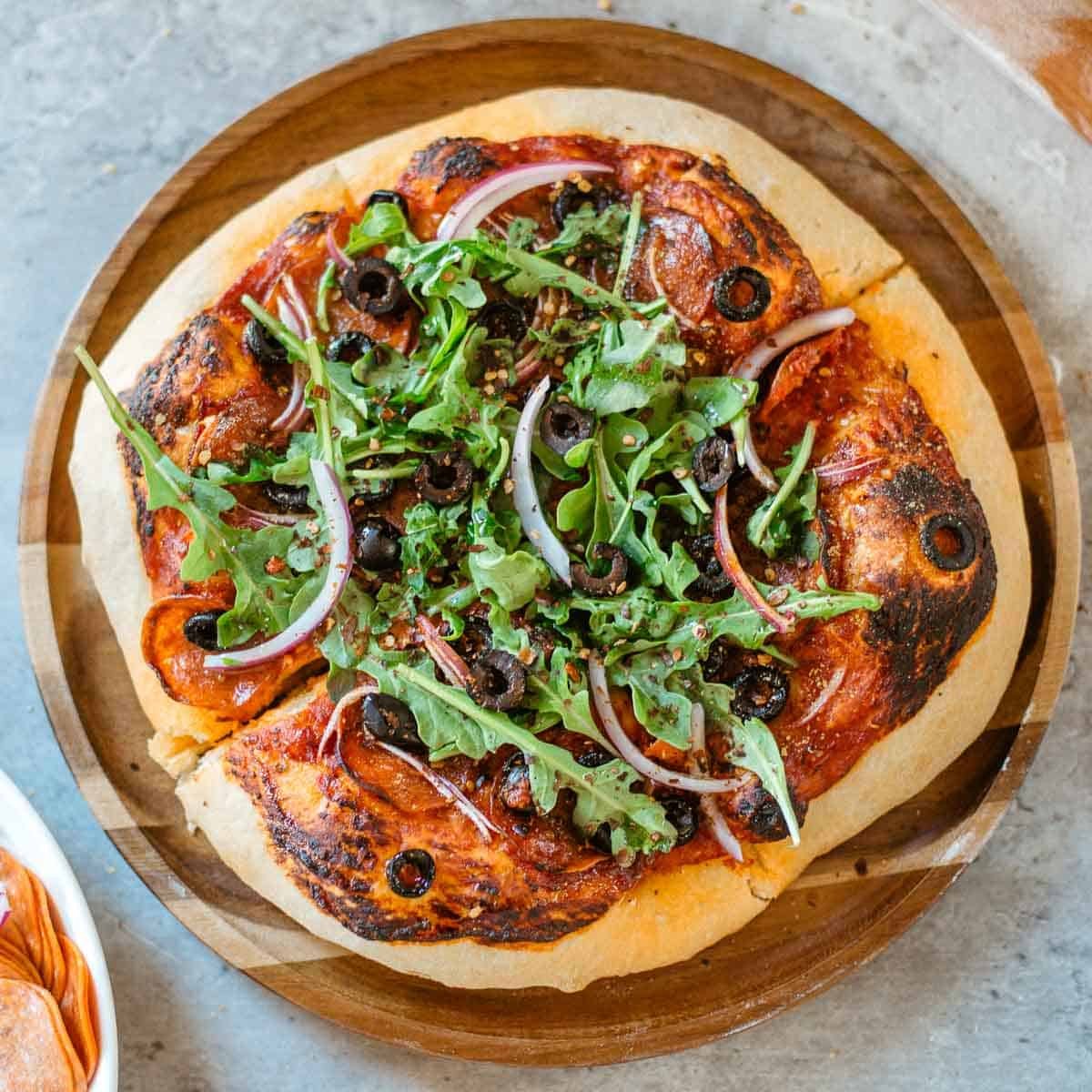 cheeseless pizza (dairy free pizza) topped with arugula.