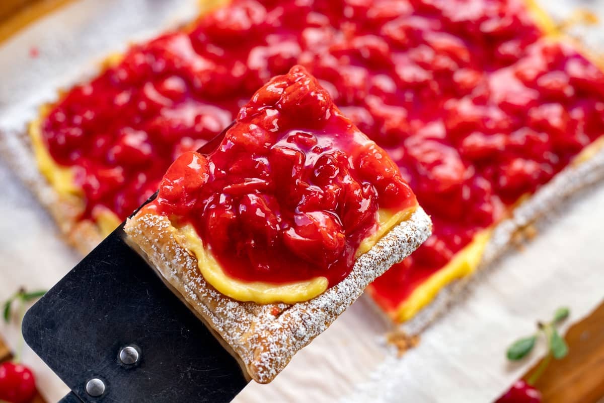 sour cherry tart with a slice being removed.