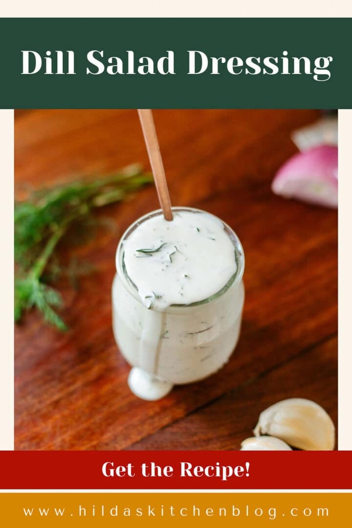 jar of dressing with spoon beside herbs and aromatics.