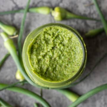 garlic scape pesto in a jar with more scapes around it.