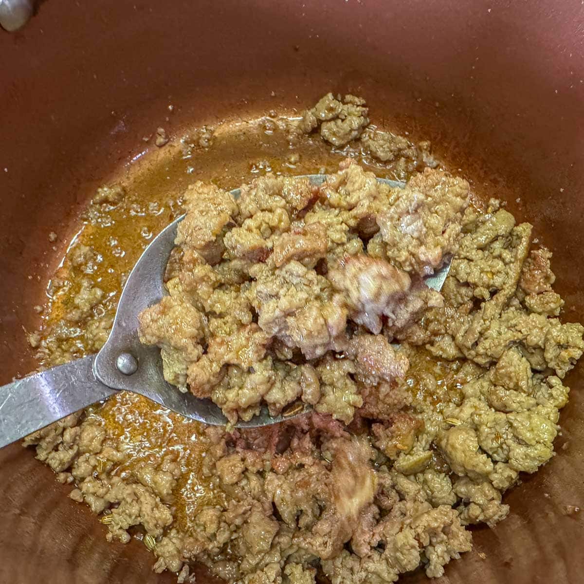 removing crumbled sausage from pot. 