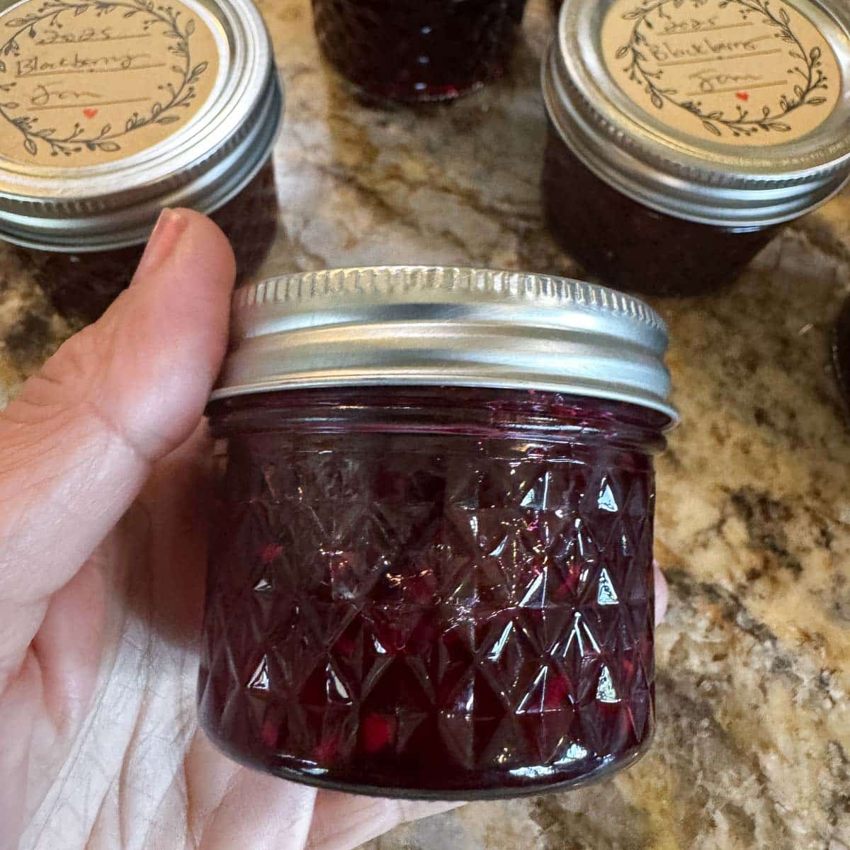 a jar of boysenberry jam being held up to camera.