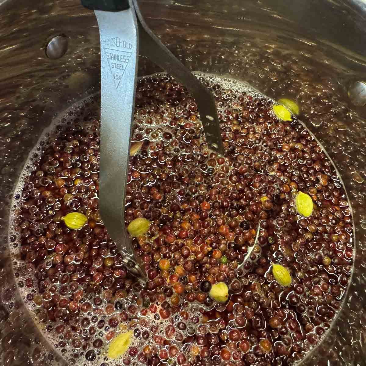 mashing elderberries in a pot.