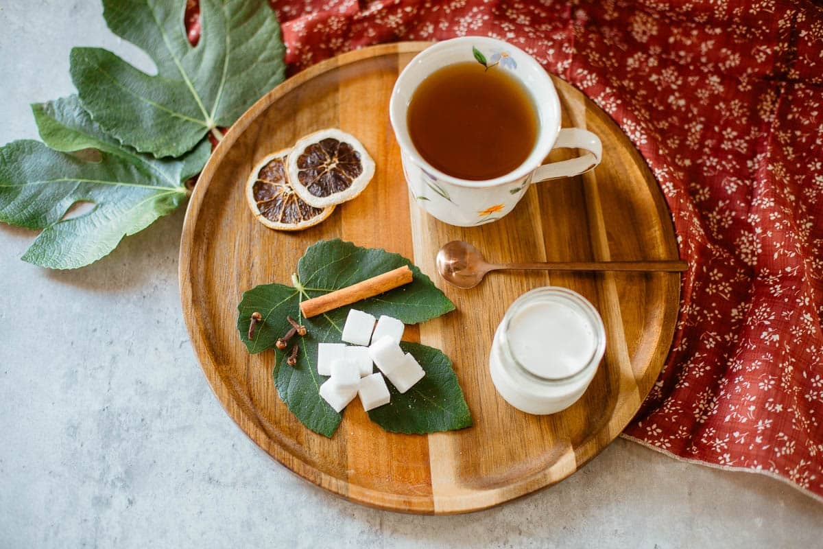 fig leaf tea on tray with fig leaves, aromatics, sugar, cream.