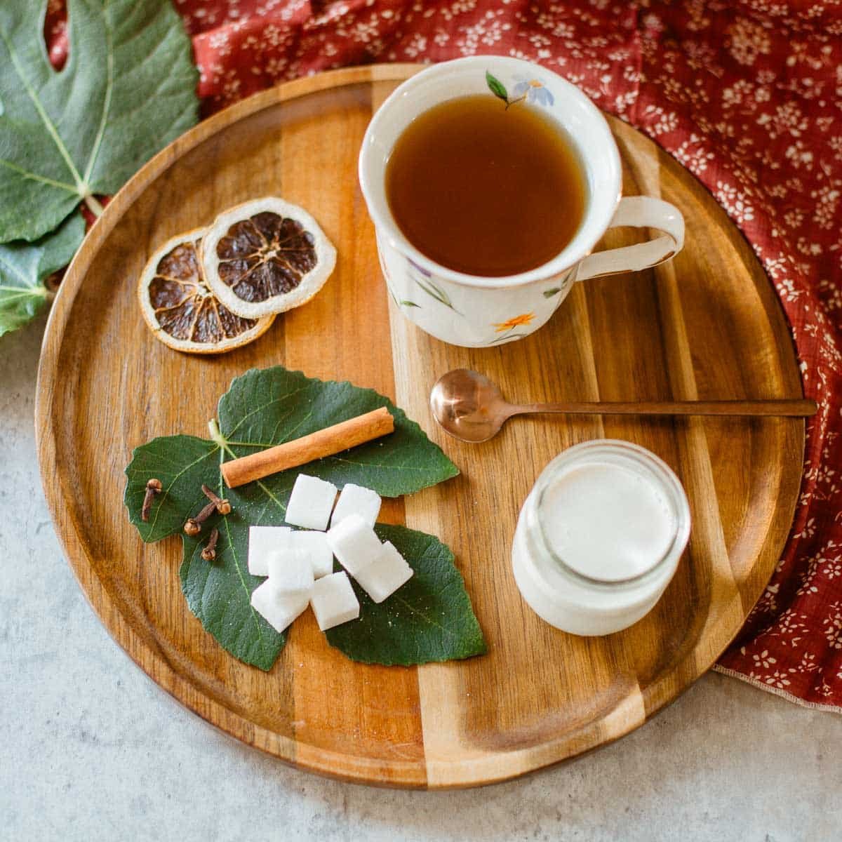 fig leaf tea on tray with fig leaves, aromatics, sugar, cream.