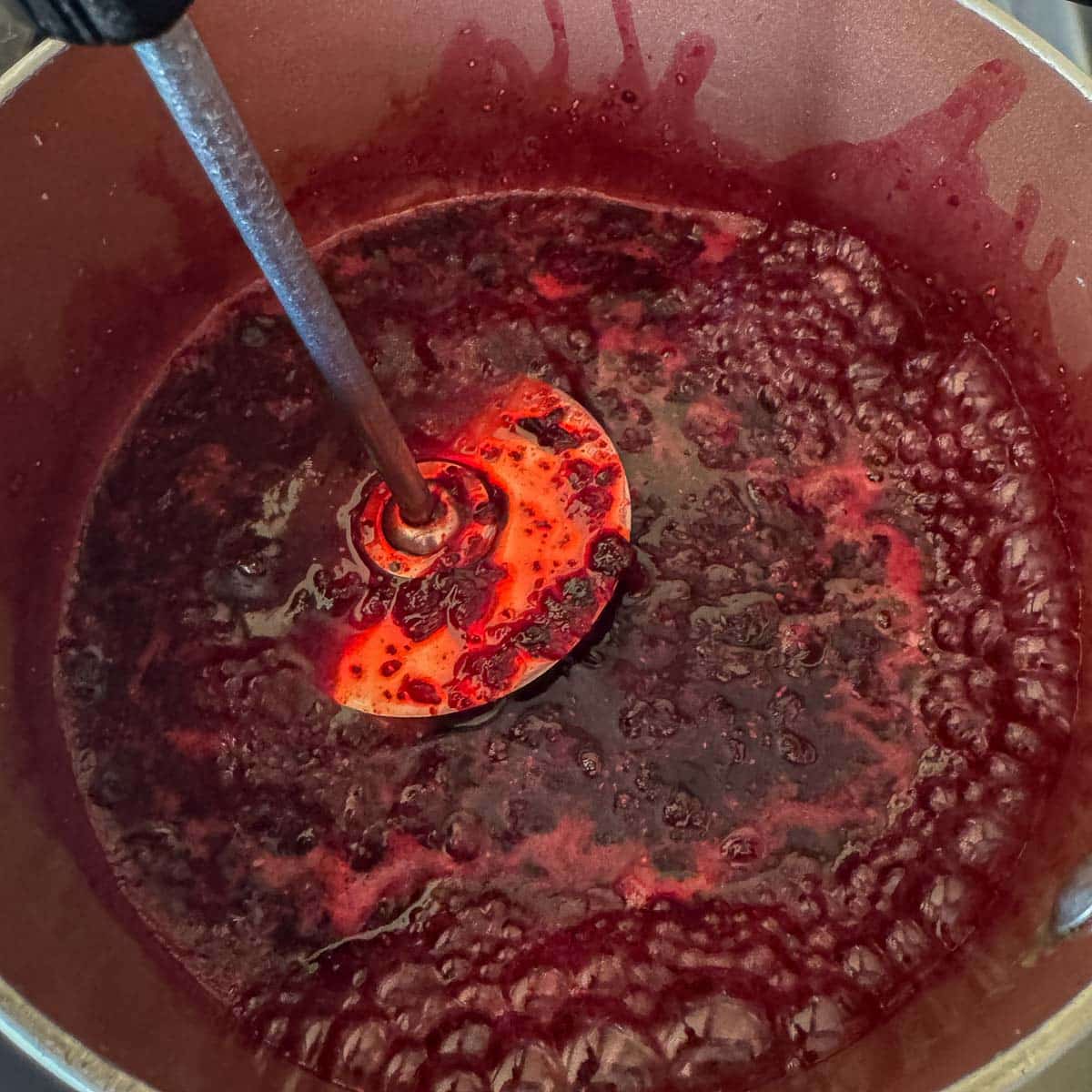 Mashing huckleberries in a pot. 