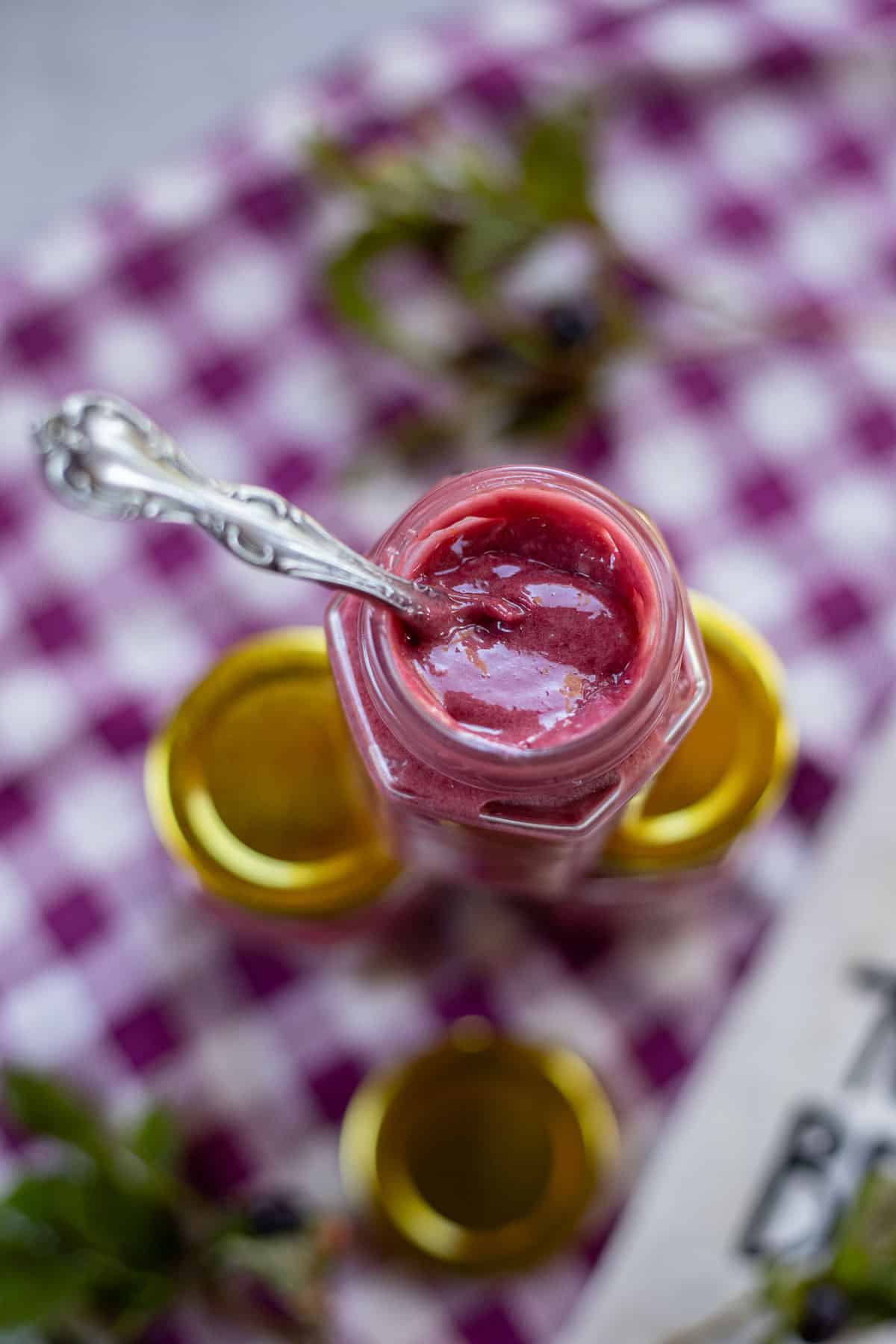 huckleberry curd in a jar with  spoon in the middle. 