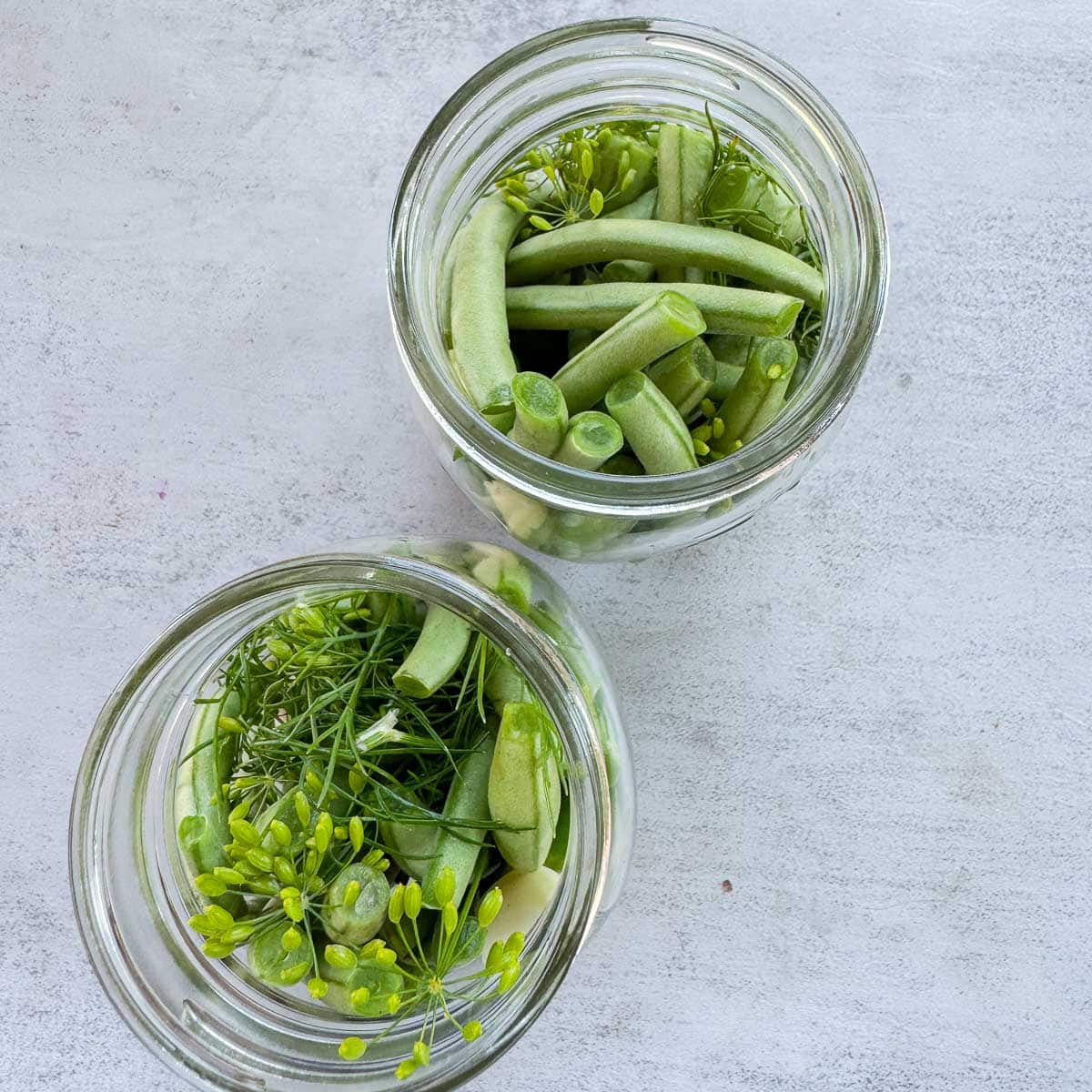 2 mason jars with green beans and dill.