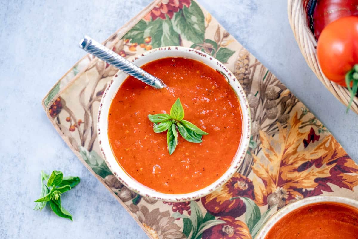 roasted red pepper soup in a bowl topped with fresh basil.