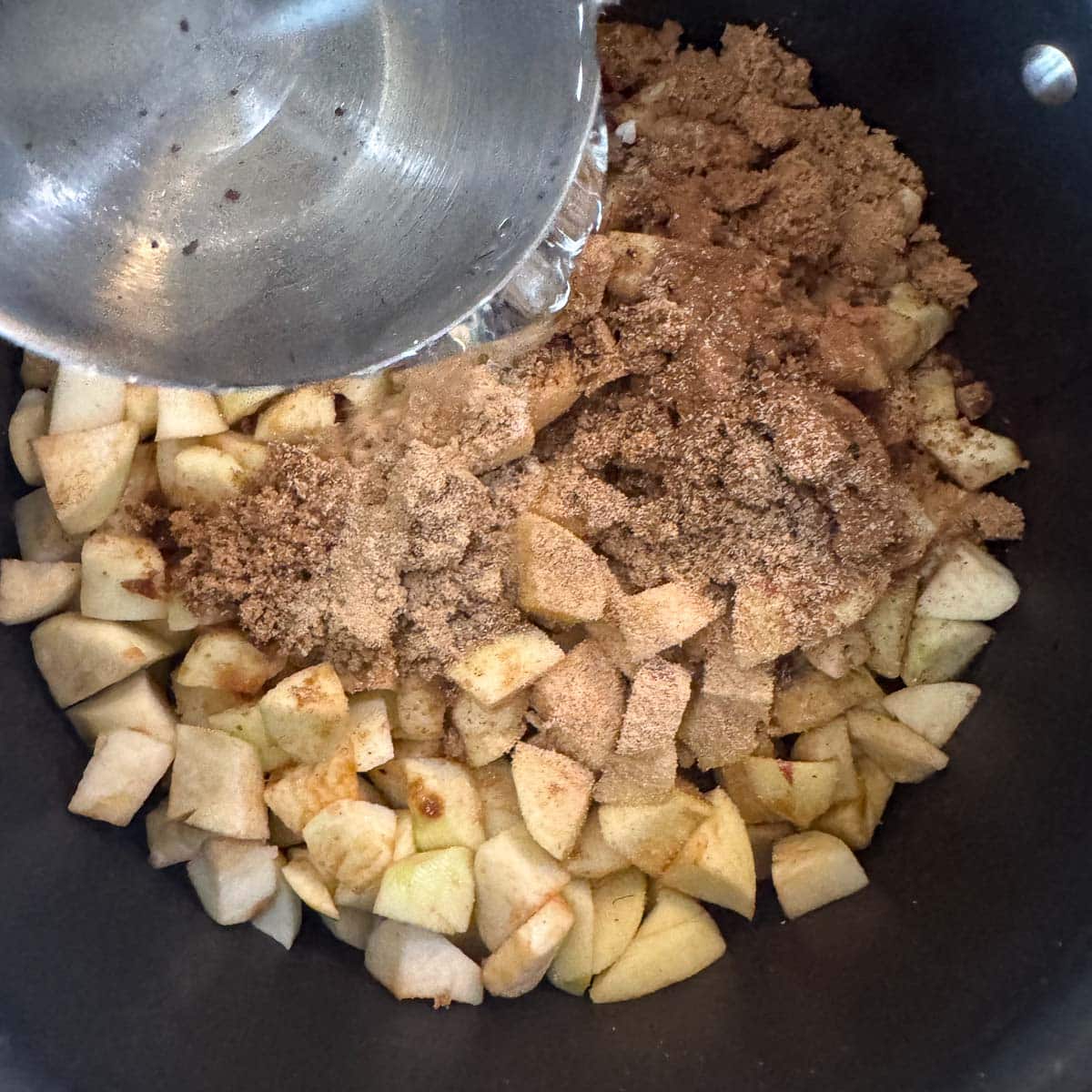 pouring water over chopped apples, sugar, and spices.
