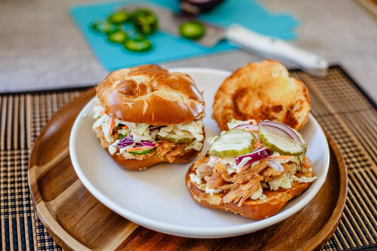 hot honey chicken sandwiches on plate beside chopped onions and jalapenos.
