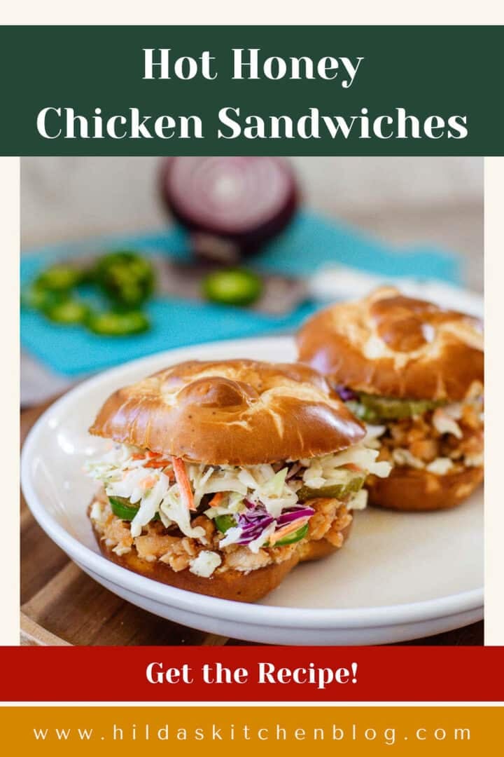 hot honey chicken sandwiches on plate beside chopped onions and jalapenos.