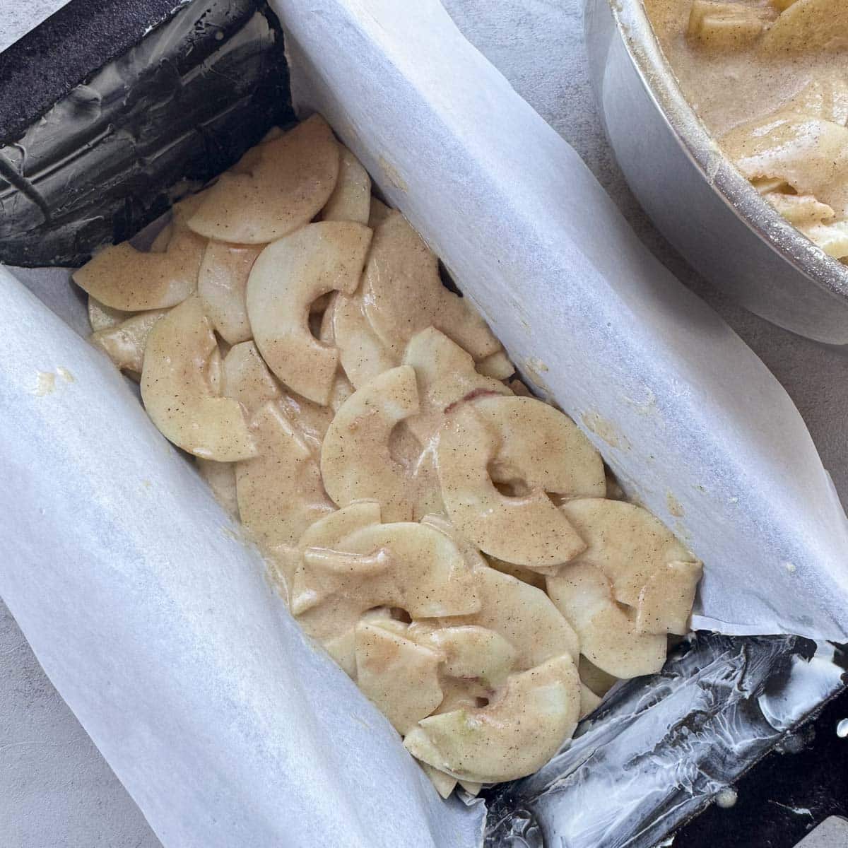 a parchment lined loaf filled with apple slices. 