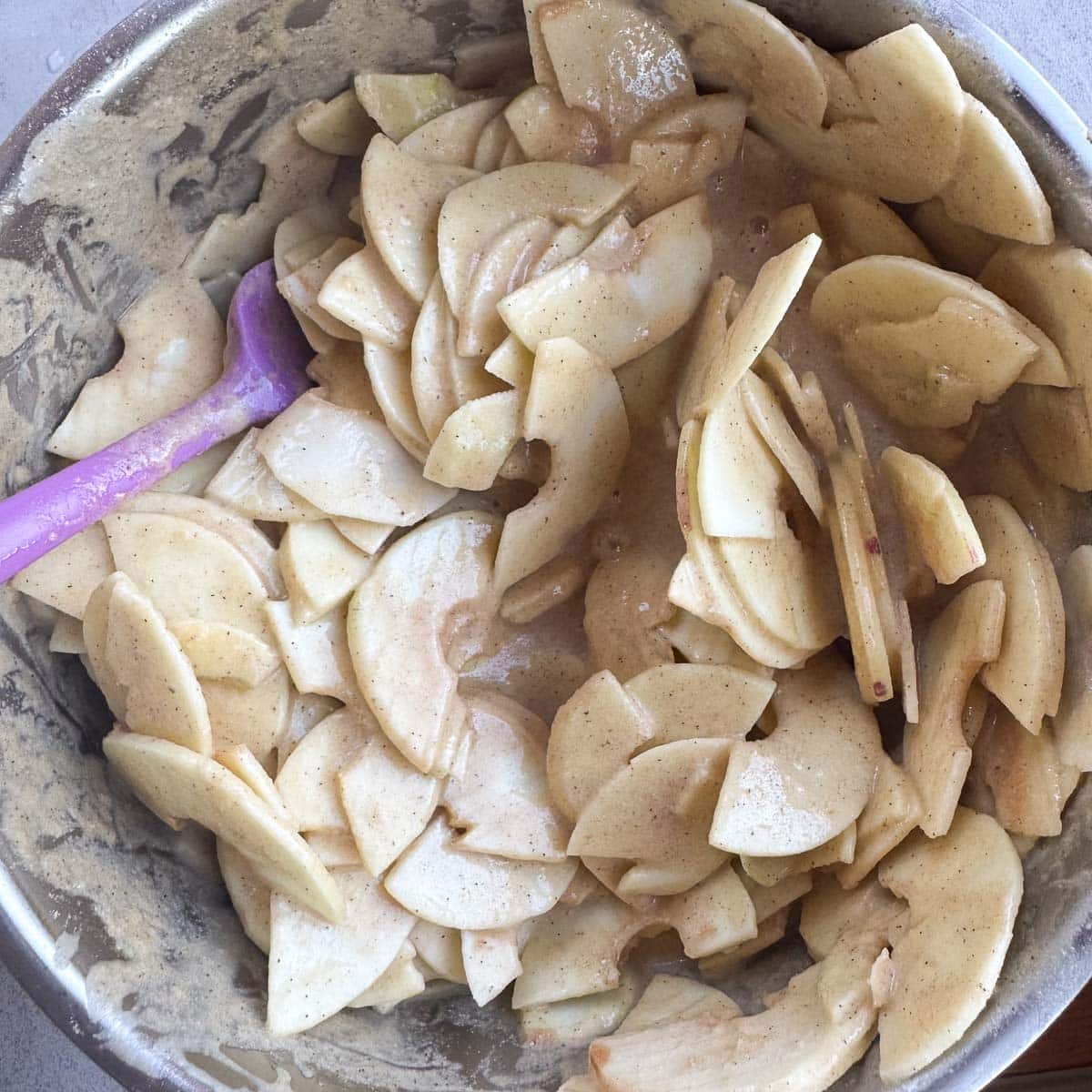 sliced apples mixed in a bowl of cake batter. 