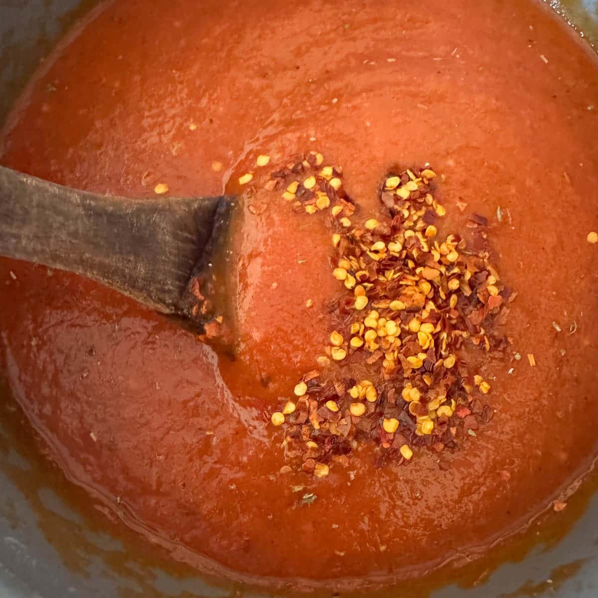roasted tomato sauce with chili flakes being stirred in.