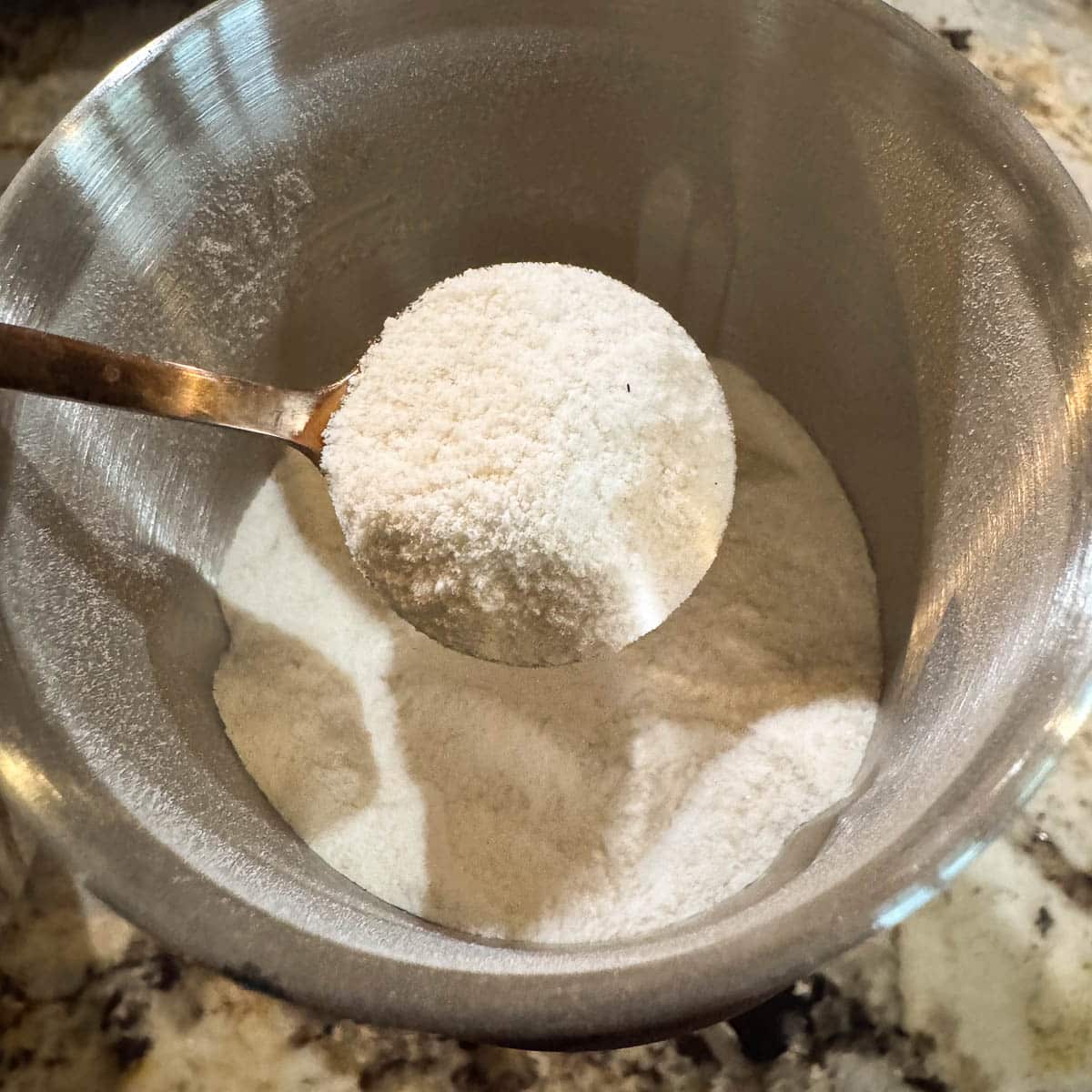 ground salt in a grinder and more in a spoon.