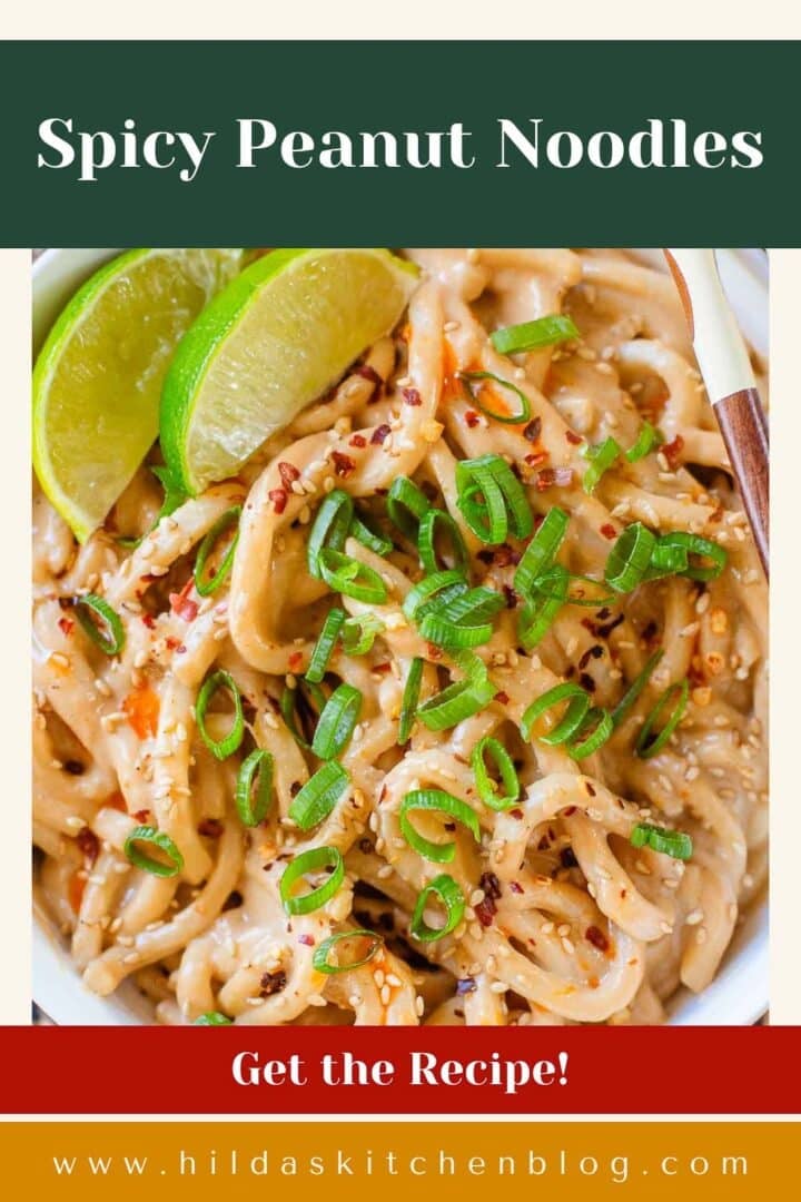 spicy peanut noodles in bowl with lime wedges.
