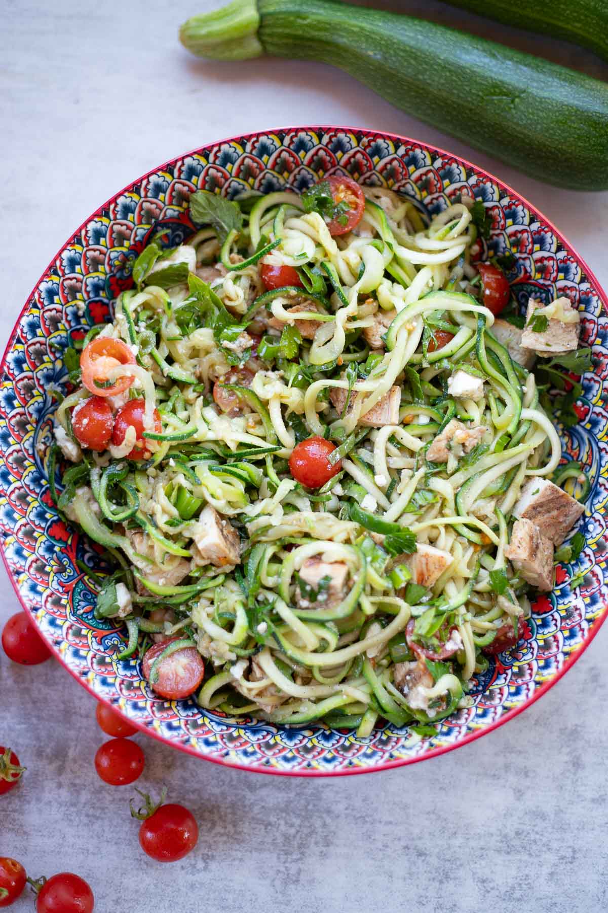 a bowl of zoodles mixed with veggies and chicken. 