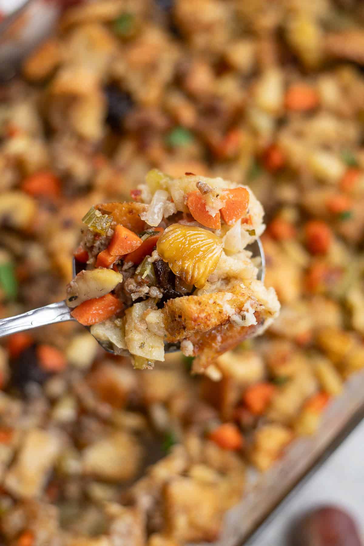 chestnut stuffing in a casserole dish with more being held up in a spoon.
