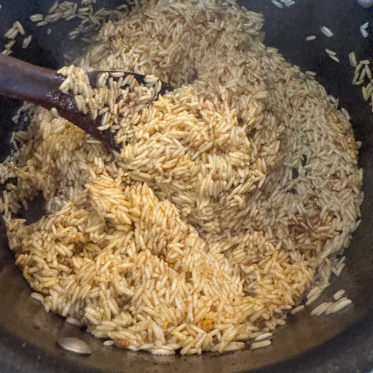 rice being stirred with a wooden spoon.