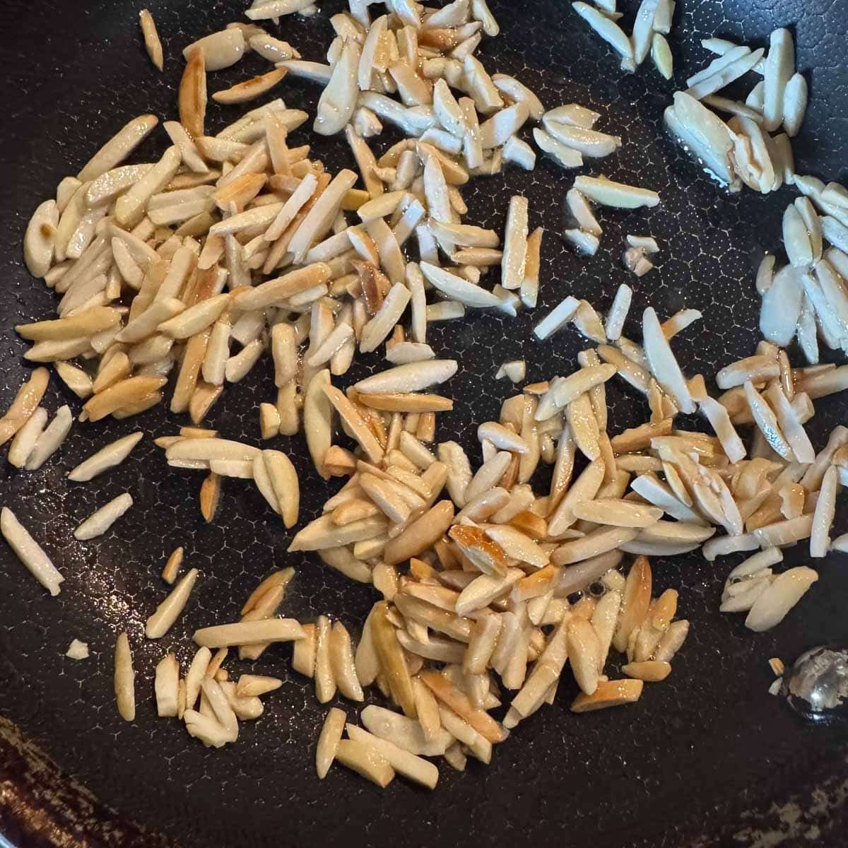 slivered almonds being toasted in a pan.