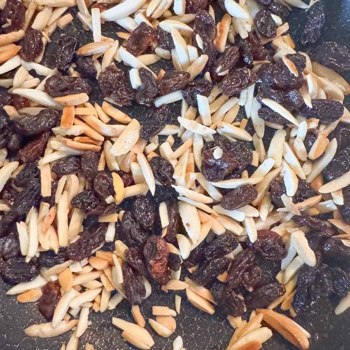slivered almonds and raisins cooking in a pan.