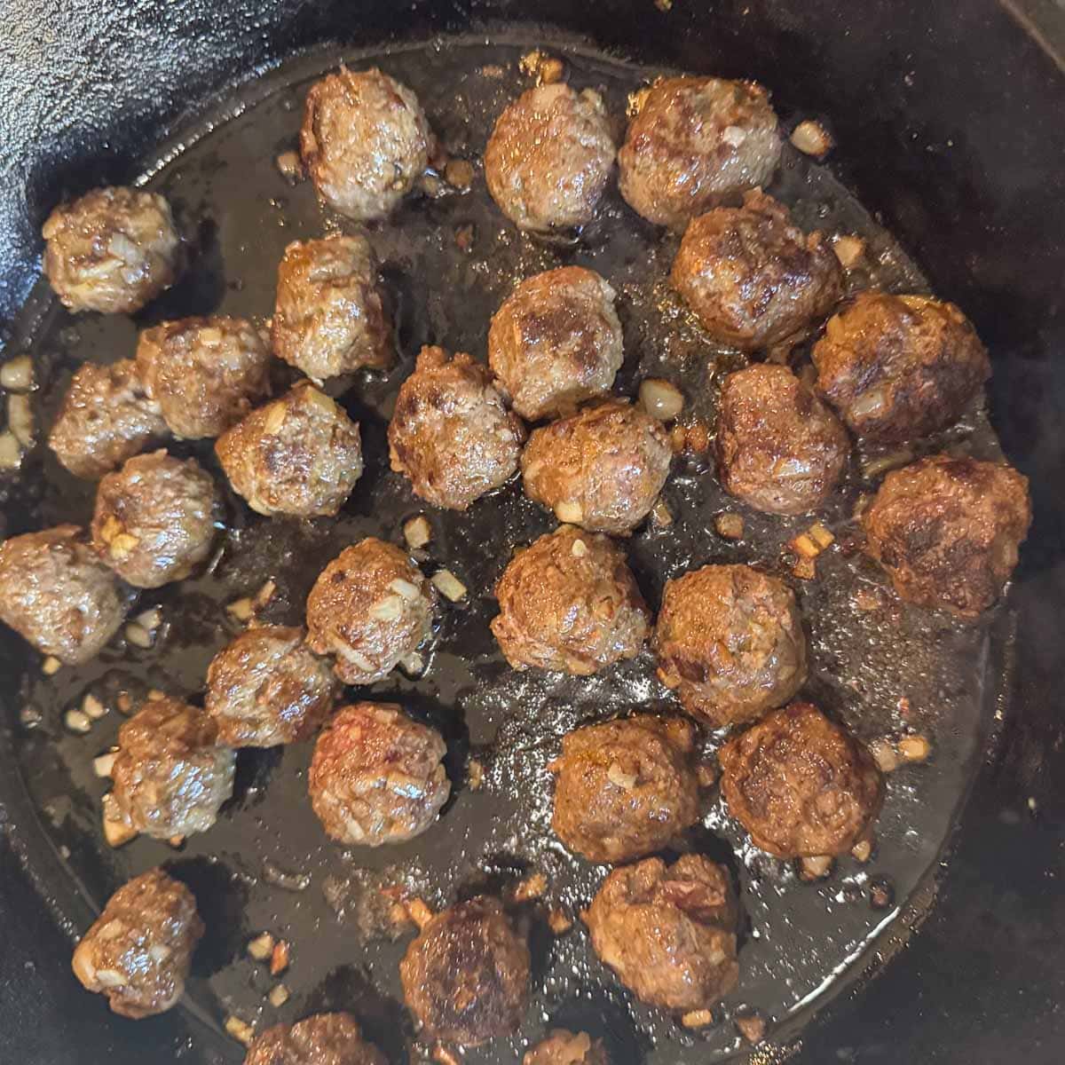 cooked meatballs in a cast-iron skillet.