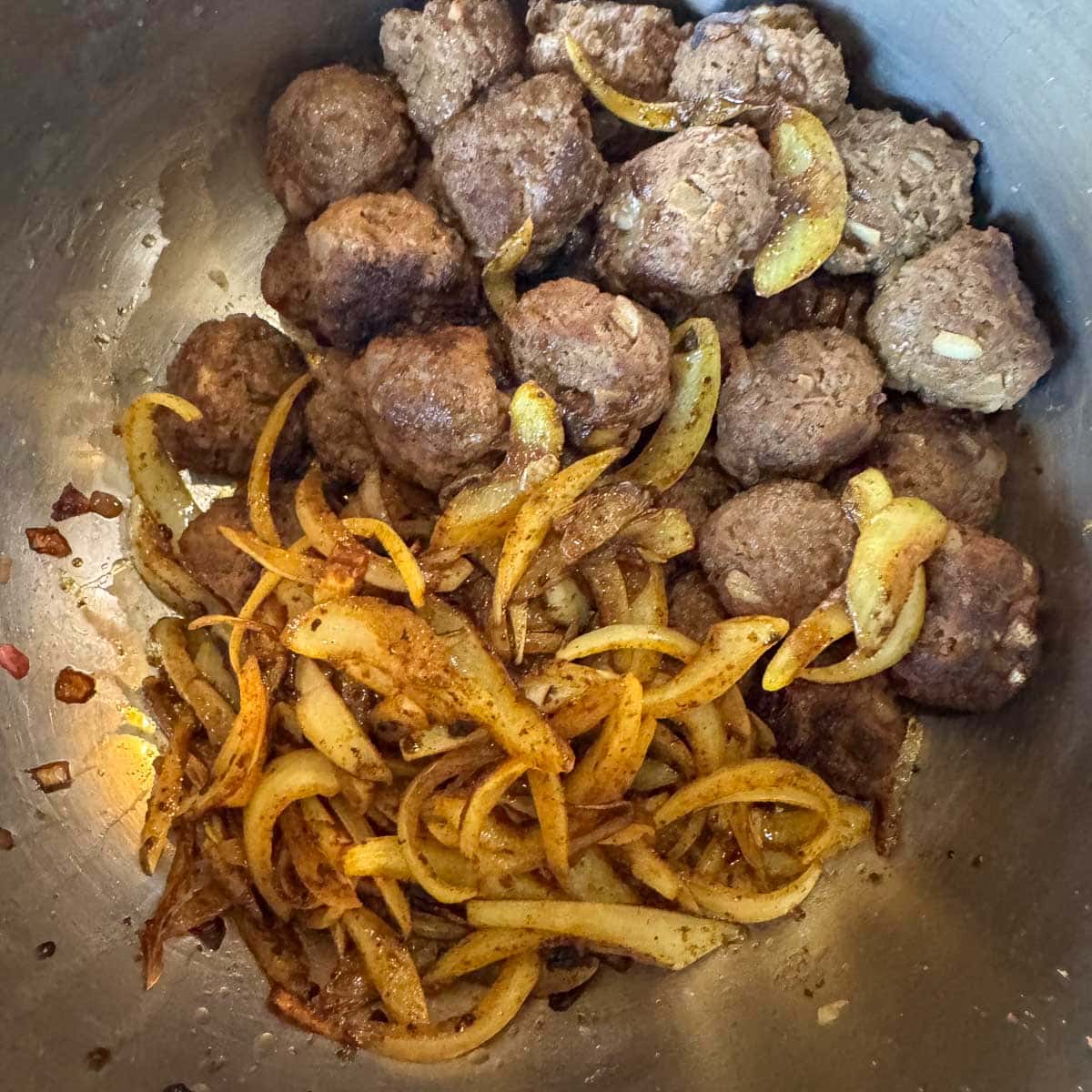 a bowl with mini meatballs and caramelized onions.