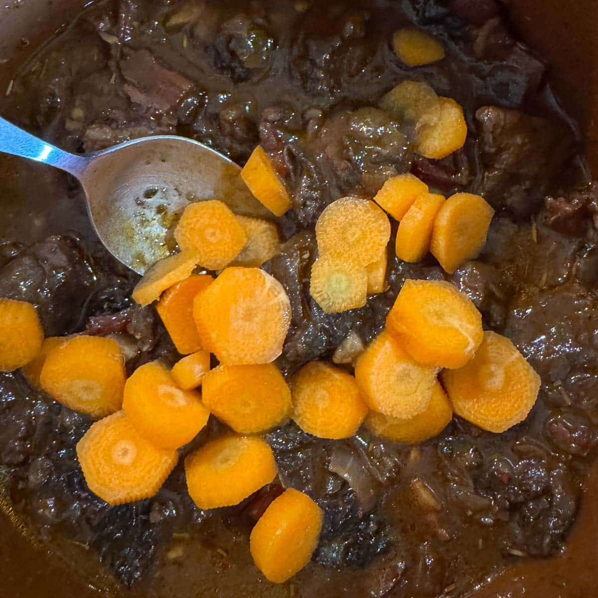 stirring chopped carrots into beef stew. 