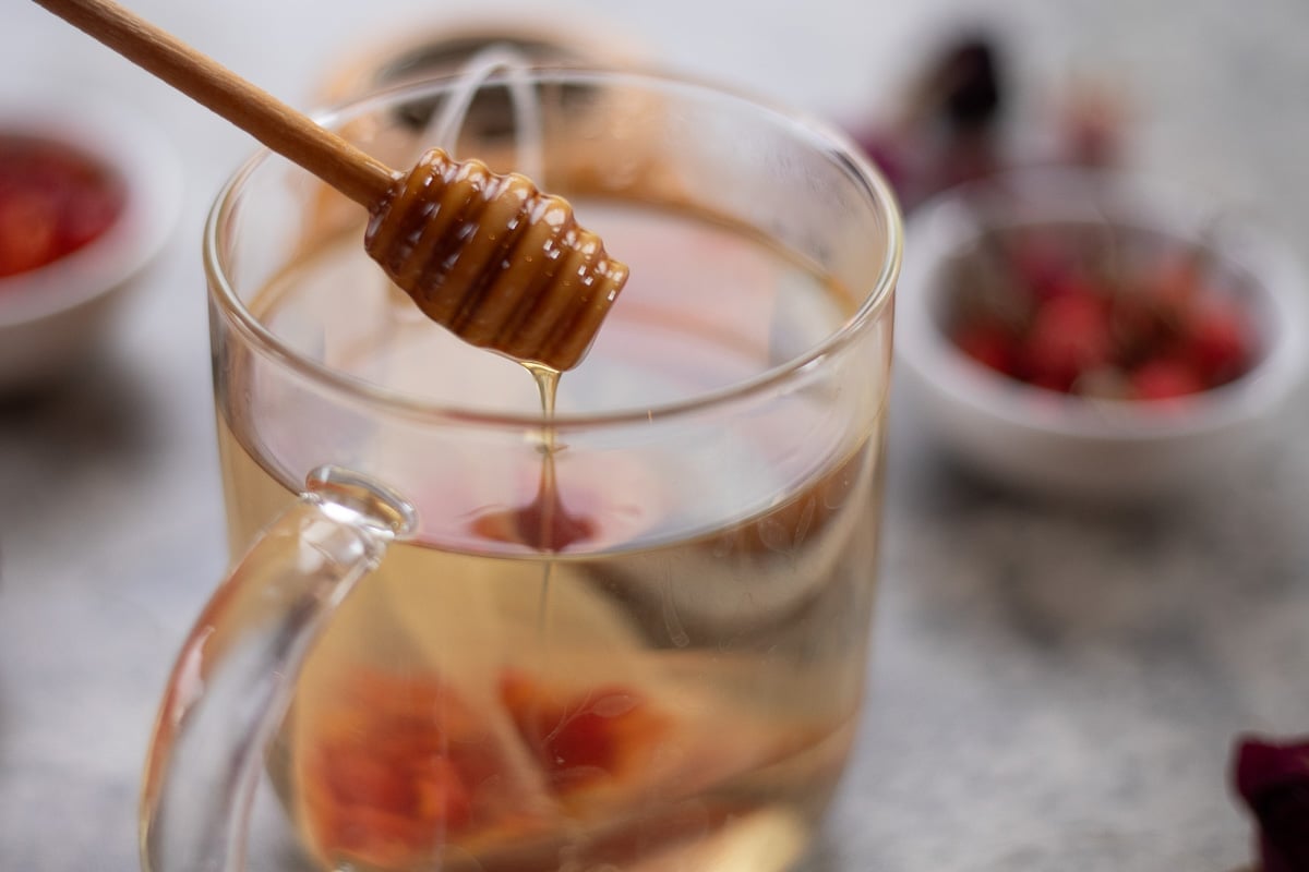 rosehip tea being sweetened with honey.