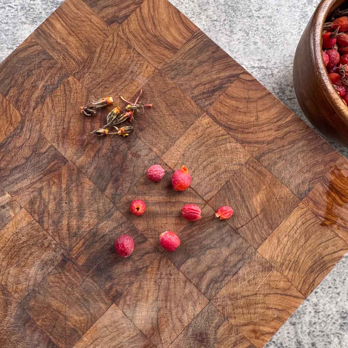 rosehips on a cutting board with blossom top removed. 
