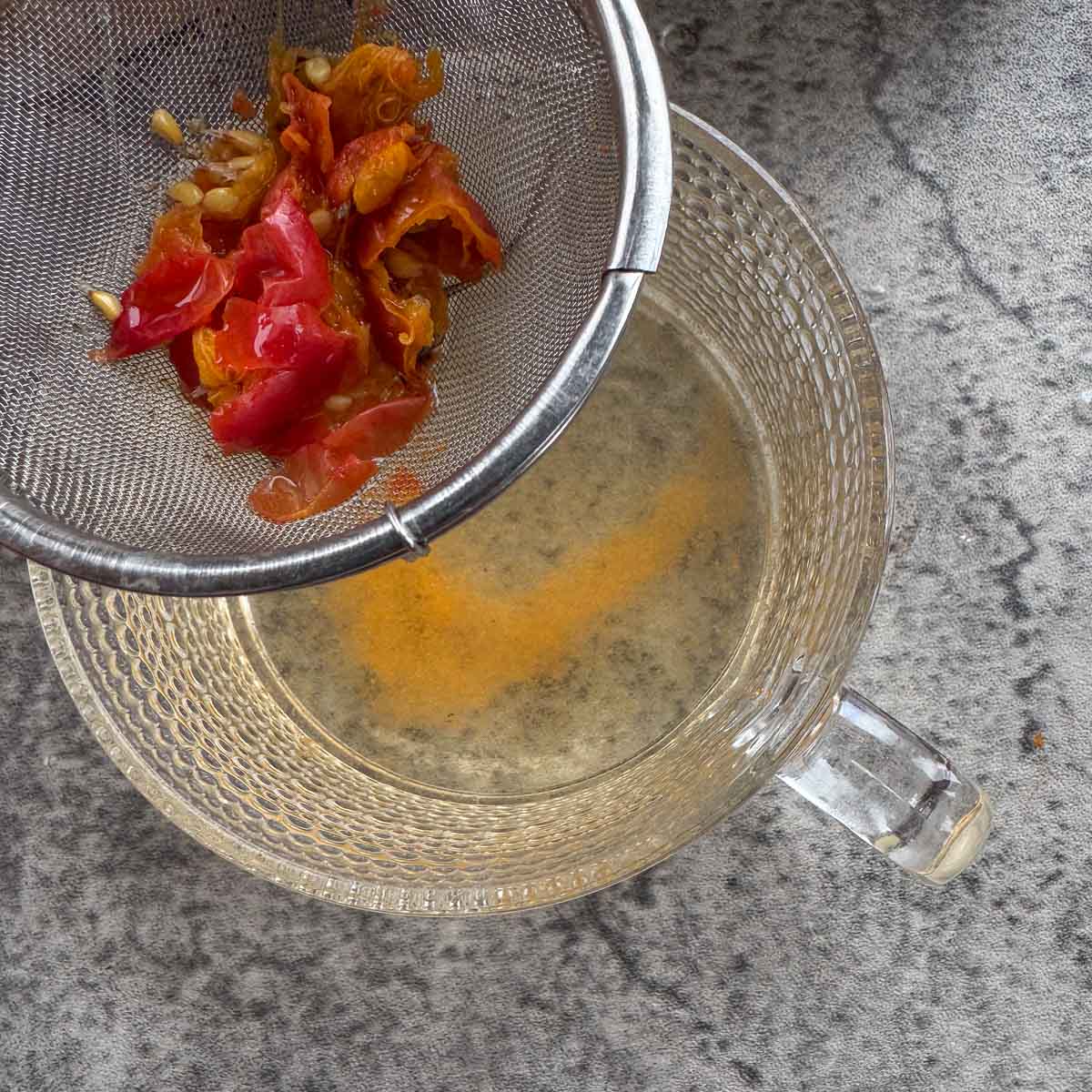 removing strainer with rosehips away from a cup of rosehips tea. 