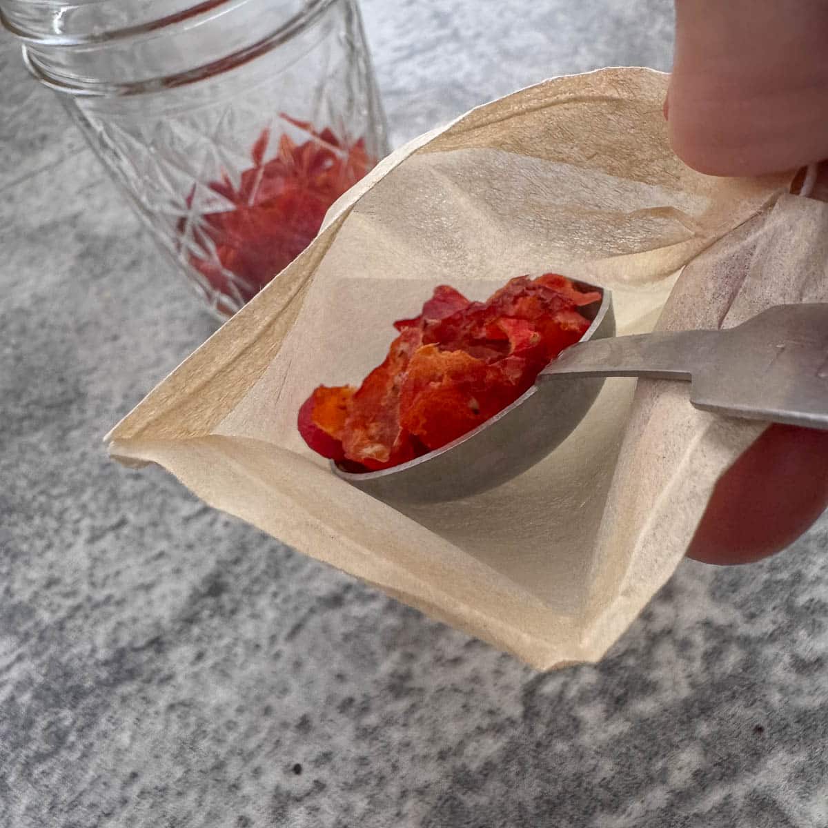 dried rosehips being placed into a tea bag. 