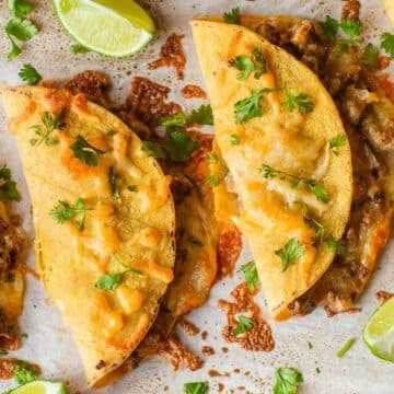 sheet pan tacos topped with cilantro beside lime wedges.