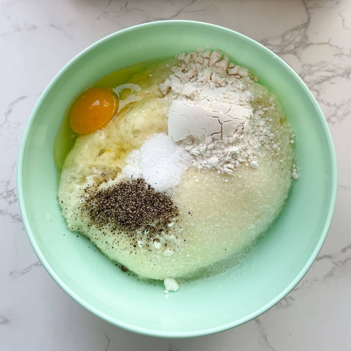 potato mixture in bowl after adding egg, flour, pepper, etc.