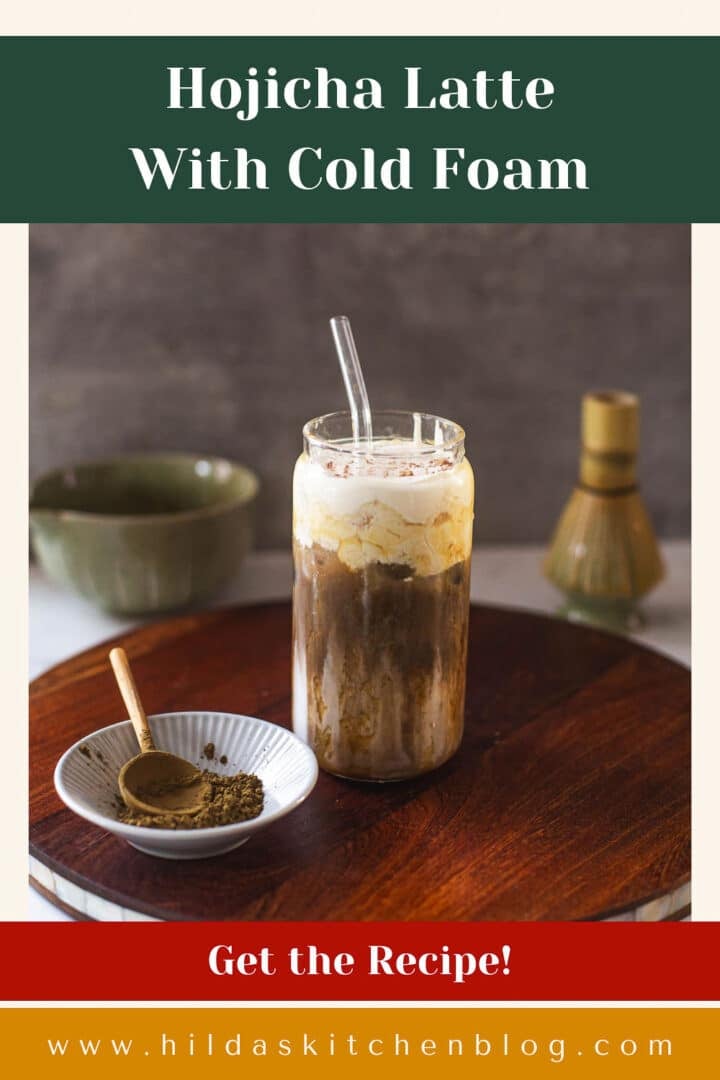 hojicha latte on wooden board with hojicha powder, whisk, bowl of tea.