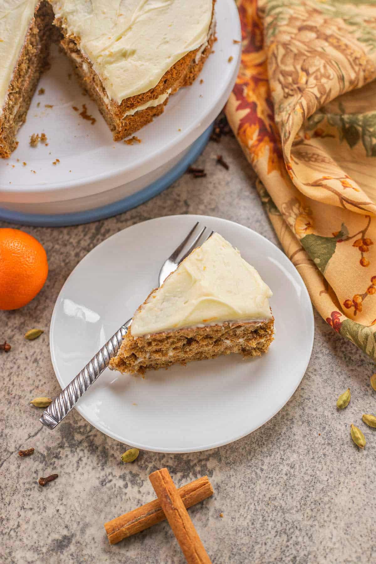kryderrkake with a slice removed and spices and an orage around it.