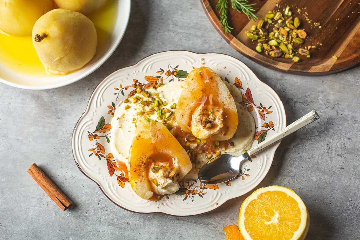 poached pears atop mascarpone surrounded by pears, orange, cinnamon, pistachios.