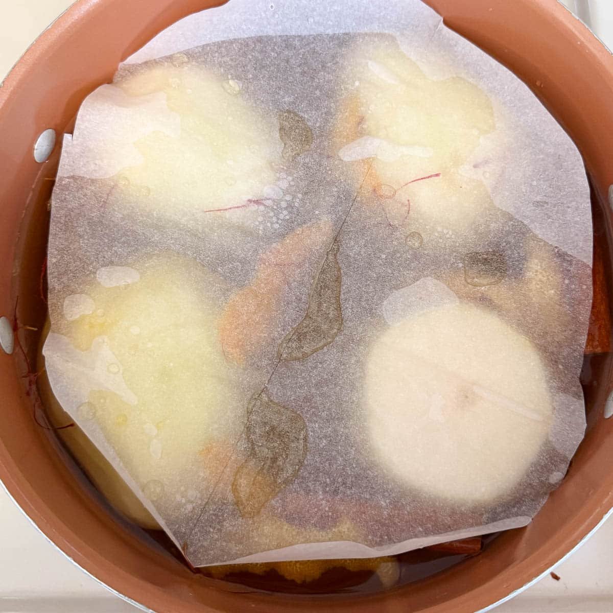 parchment paper keeping pears submerged.